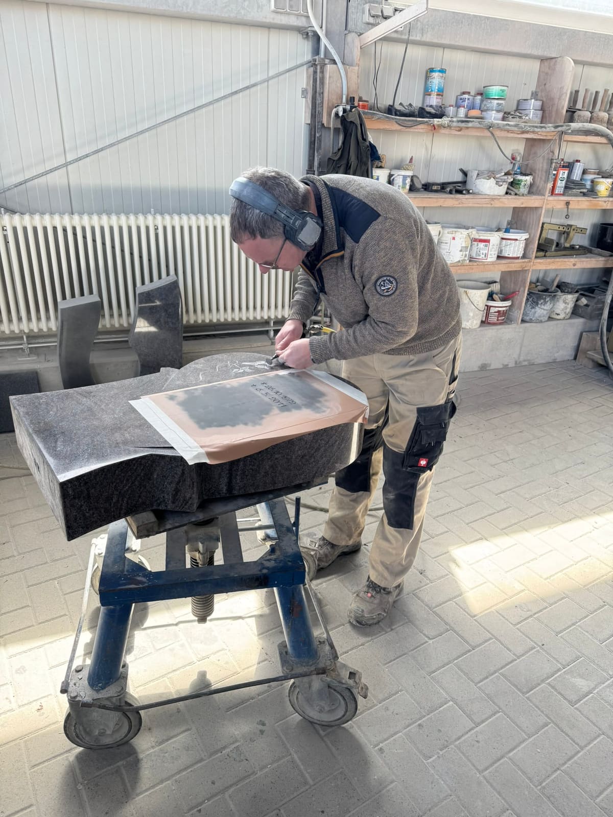 Steinmetz beim Einschlagen der Inschrift in der Werkstatt